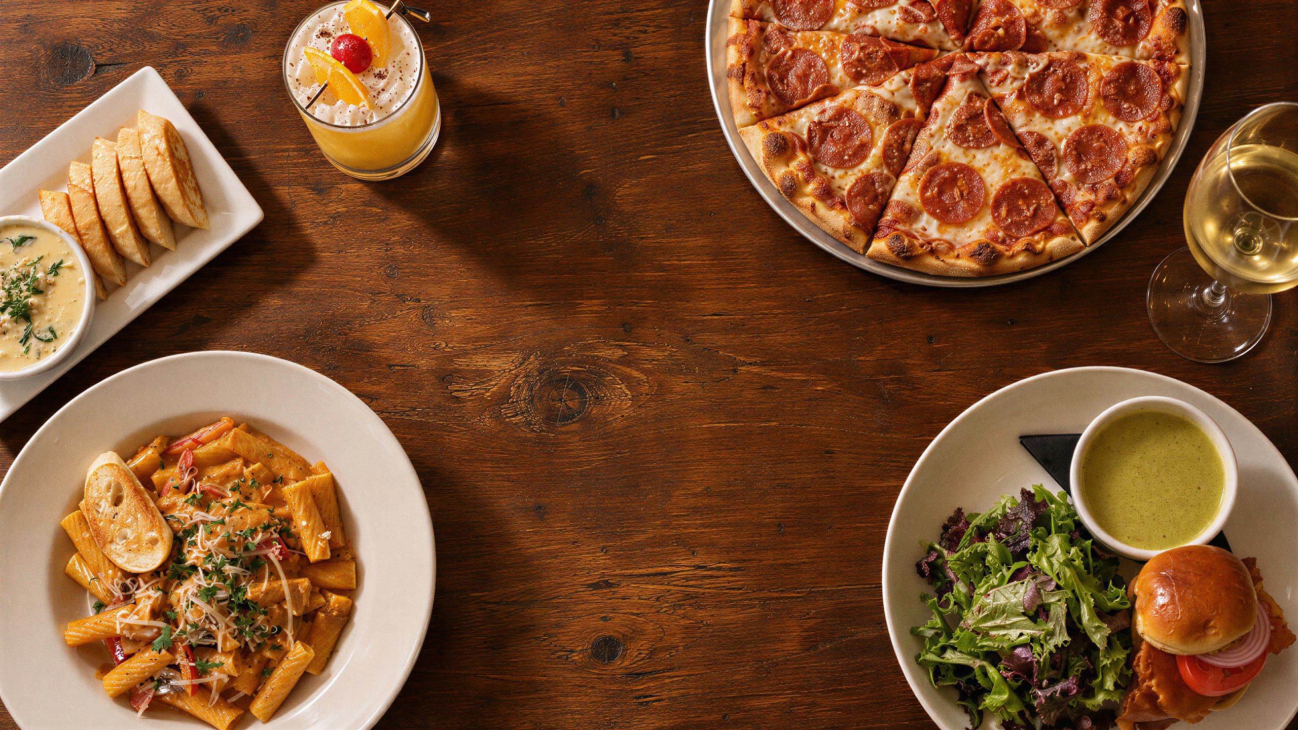 Pasta, pizza, salad, and cocktails on a wooden table