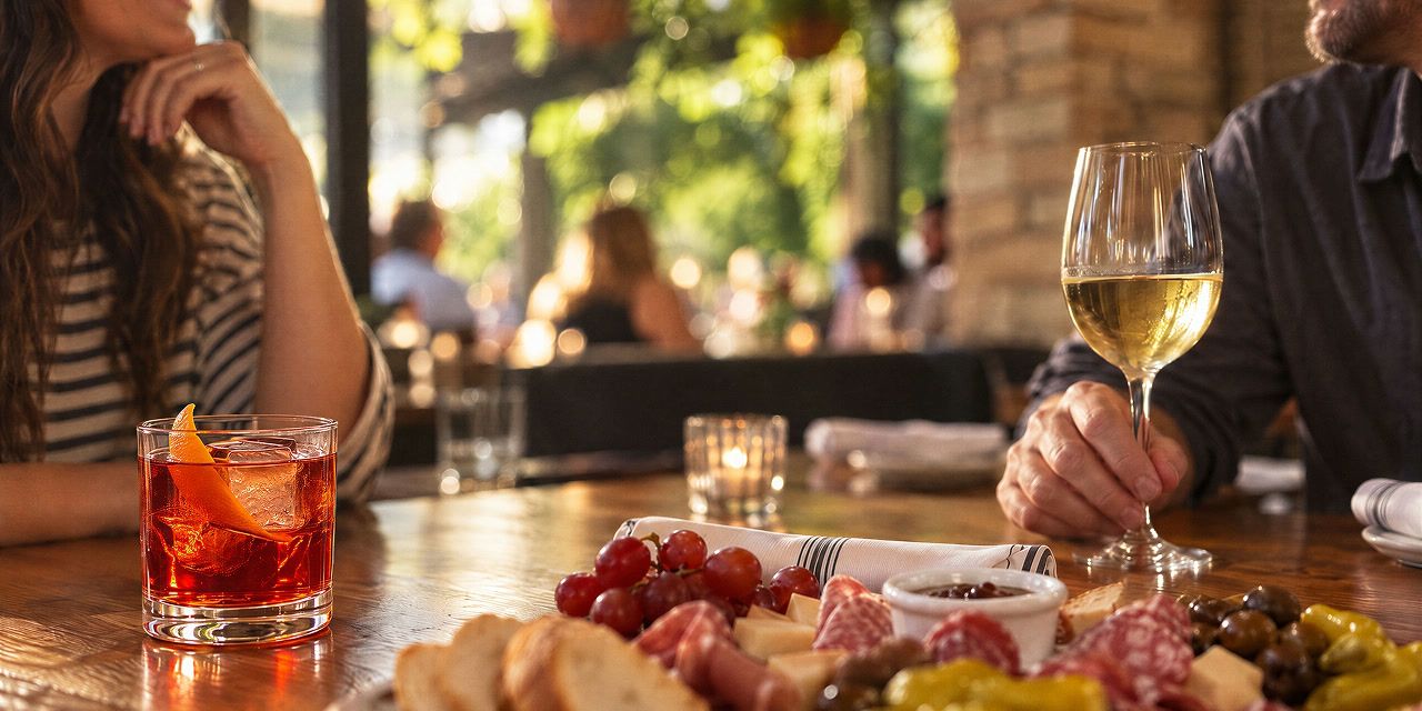 Cocktail, white wine, and a charcuterie board on the bar