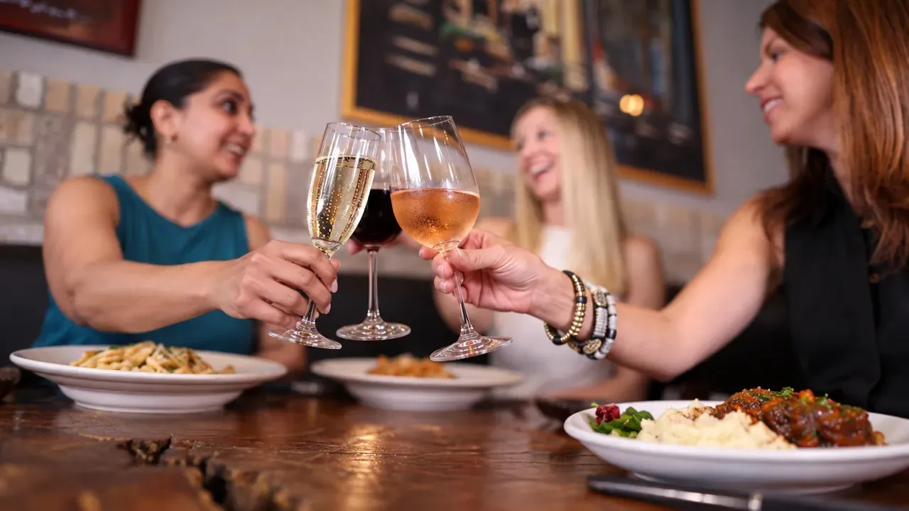 Friends toasting with glasses of white, red, and rosé wine over dinner